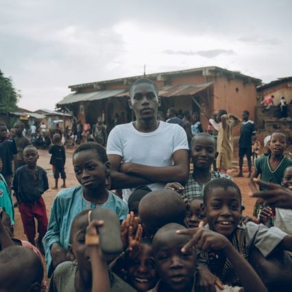 A dynamic scene of children and adults in a vibrant village setting in Nigeria.